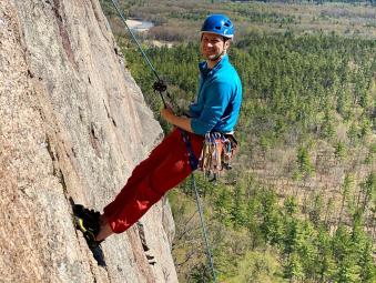 Male climber standing on side of rock leaning back on his rope